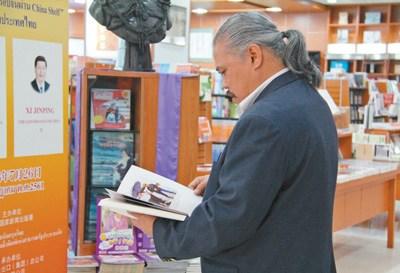 中国侨网“中国书架”旁，一名当地读者正在认真阅读中文书籍。 本报记者 张志文摄   
