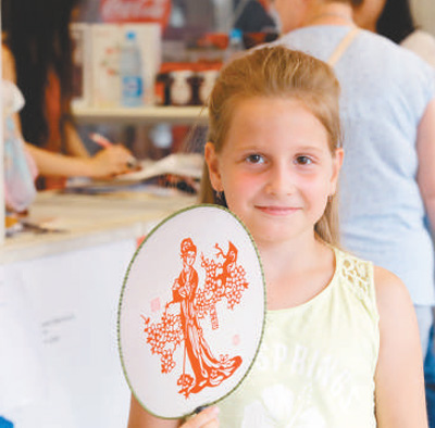 在“北京日”老字号展卖活动中，一位俄罗斯小朋友购买了一把工艺品扇子。 　　本报记者 王斯雨摄