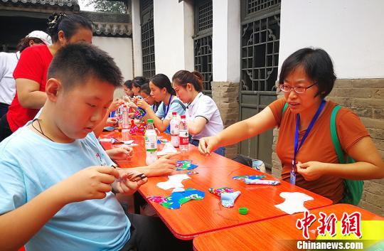 太原市侨联党组书记李锦指导营员制作布老虎?！⊙罱苡?摄