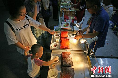 7月14日，市民在澳门展区品尝香记肉干?；盍Π拿磐乒阒茉?018天津“华博会”同期举办，展区设有210个展位，包含澳门风貌、澳门创意美食、时尚文创、家居用品等六大展区，让民众感受不一样的澳门风情。<a target='_blank' href='http://www.chinanews.com/'>中新社</a>记者 佟郁 摄