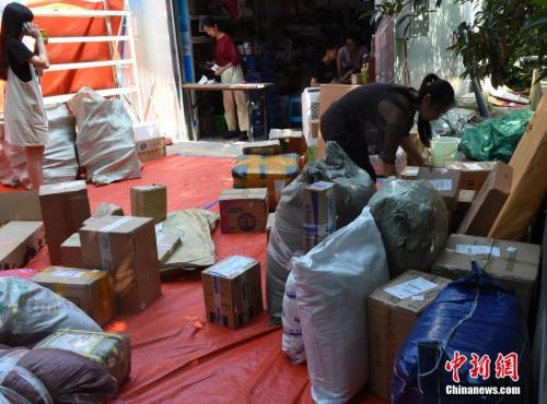 工作人员正在整理送到快递点的包裹。 周毅 摄