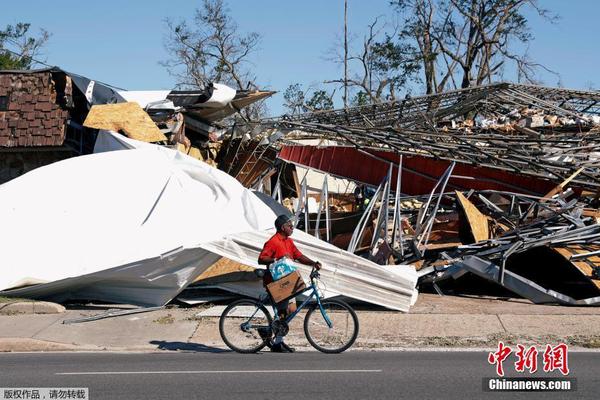图为当地时间10月14日，男子骑车经过一片废墟。