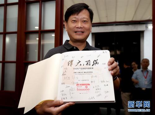 在中共一大会址纪念馆内，今年的第100万名观众刘凯在展示获赠的精装图册《伟大开端》（8月25日摄）。图册扉页上盖有“第1000000名观众”纪念章，还有纪念馆全体工作人员的签名。新华社记者 刘颖 摄