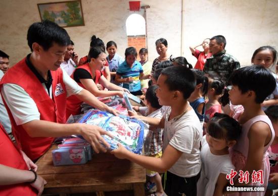 志愿者向留守儿童赠送书包、文具盒。 周亮 摄