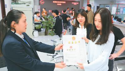 河北省承德市网络代购经营者陈晨(右)从工作人员手中接过带有统一社会信用代码的营业执照。 刘环宇摄(人民图片)