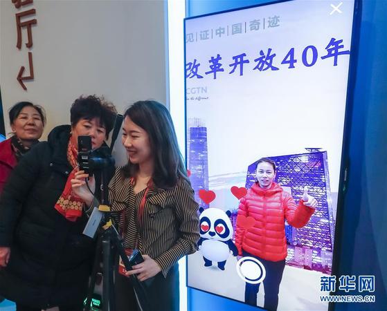 11月20日，在 “伟大的变革——庆祝改革开放40周年大型展览”的壮美篇章展区，观众在体验中央广播电视总台的AR体验项目，与一只“CGTN熊猫”互动，并拍摄照片。