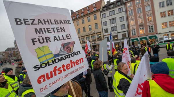 图为抗议人士高举写着“为所有人支付房租”的标语牌