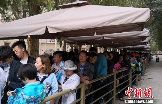 图为2018年8月中旬，莫高窟前等候参观的应急游客排成近1公里长队。(资料图) 冯志军 摄