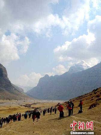 西藏阿里地区独特的自然风光及具有深厚文化底蕴和举世闻名的人文景观，吸引着越来越多的游客走进阿里，旅游业也让当地民众得到越来越多的实惠。图为国内外游客及信众在冈仁波齐神山脚下。　尼玛顿珠 摄