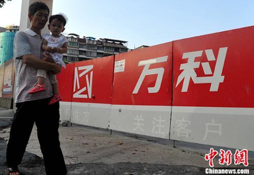 资料图：民众从万科某楼盘工地旁经过。<a target='_blank' href='http://www.chinanews.com/'>中新社</a>记者 张斌 摄