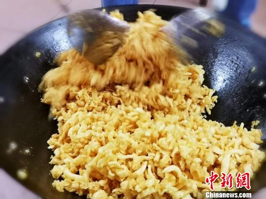 浇上糖浆的玛仔需迅速用锅铲拌匀 李晓春 摄