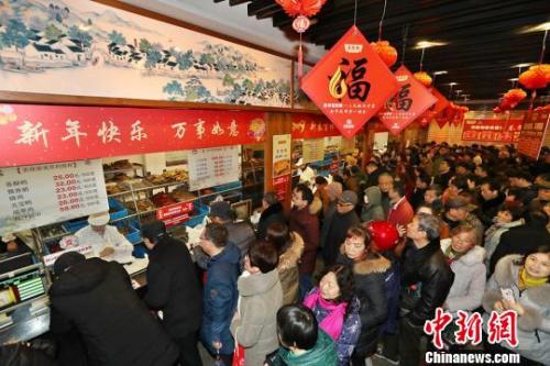 资料图：民众排长队购熟食备年货?；络?摄