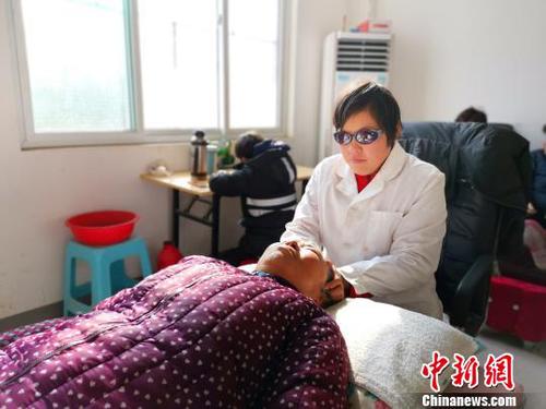 在社区服务中心，刘奉智母亲为村里人按摩，刘奉智在一旁写作业?！『卵Ь?摄