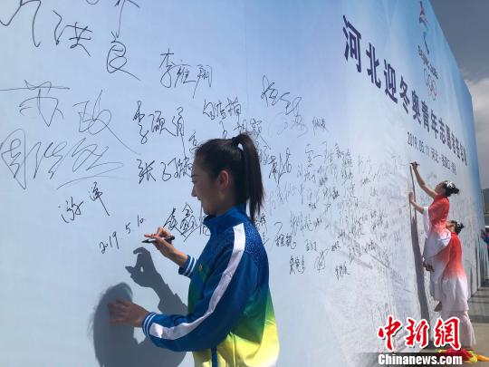 图为河北迎冬奥青年志愿者、张家口机械工业学校教师游洋在启动仪式现场主题背景墙上签名。　宋敏涛 摄