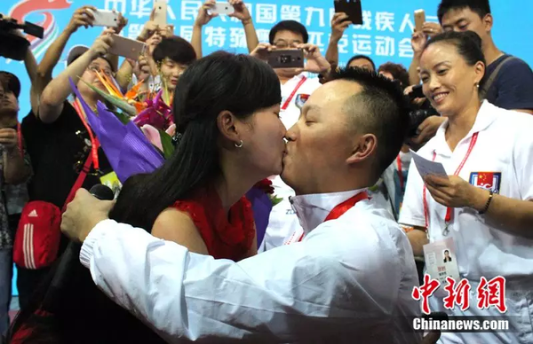 2015年9月18日，在地震中失去双腿的四川游泳队运动员“无腿蛙王”代国宏，在残运会赛场向女友苏思妙求婚成功。中新社发 钟欣 摄