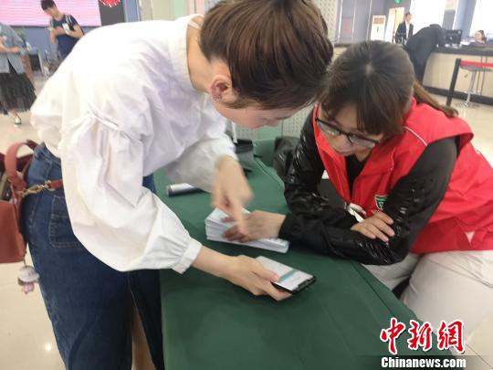 市民向志愿者咨询如何使用电子社?？?。　张煜欢 摄
