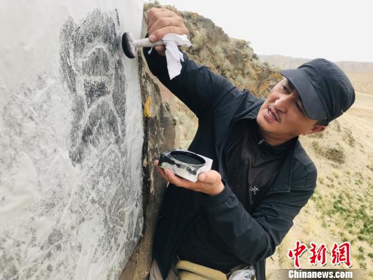 图为杜成峰按照岩画线条走向用拓包开始描边。　朵丹 摄