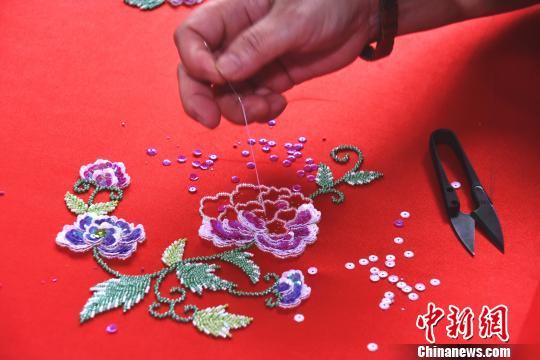 在绣工的穿针引线下，花朵逐渐“绽放”在罗缎上?！〕铝?摄