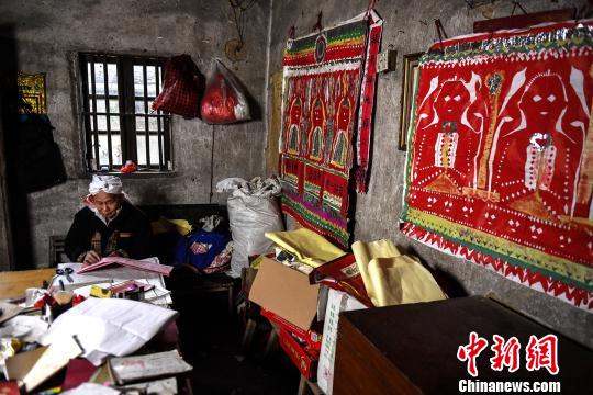 盘良安的“工作室”内堆满了祭祀用的道具、典籍，墙上张贴着盘王图?！±盍?摄