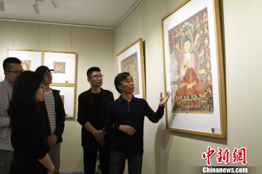 图为主创者高志勇向参观嘉宾介绍拍摄作品?！≌岳?摄