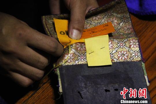 图为罗布林卡管理处工作人员将编号缝在古籍外侧?！≌岳?摄