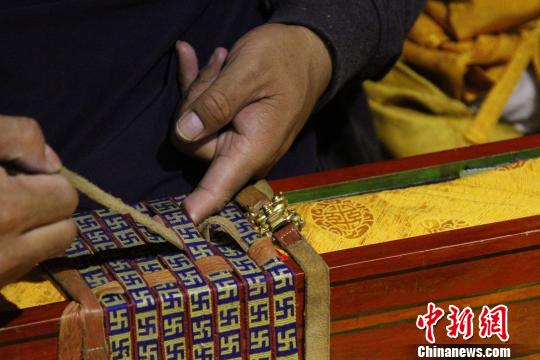 图为罗布林卡管理处工作人员将普查登记完的一函古籍封装?！≌岳?摄