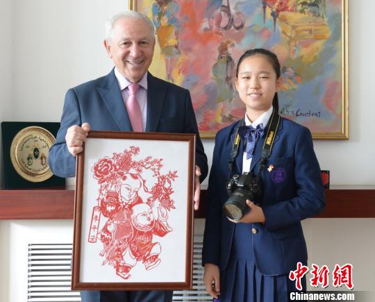 “2019丝路新语？中外文化小使者巡礼”活动在京启动。图为中国文化小使者向摩洛哥王国驻华大使阿齐兹？梅库阿尔赠送中国剪纸。主办方供图