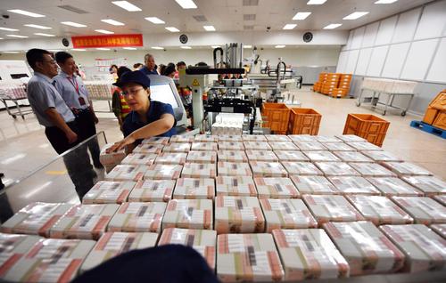 工作人员对塑封好的20元钞票进行封装操作。