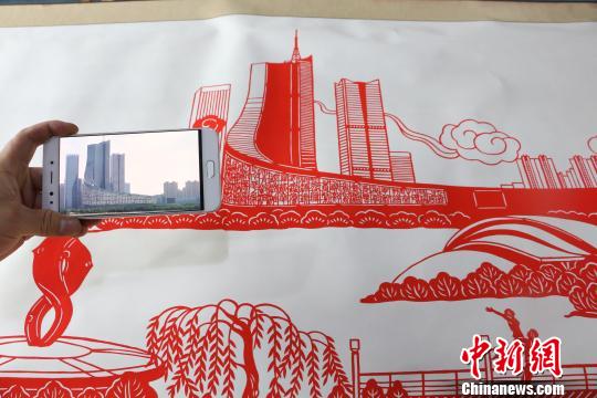 图为丁健对比照片与剪纸作品?！∠挠?摄