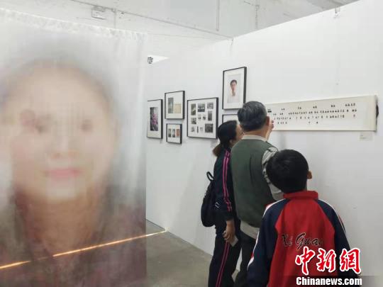 在第19届中国平遥国际摄影大展柴油机展区的一角，一张大幅的人像彩画吸引来往游客驻足拍照。　杨佩佩 摄