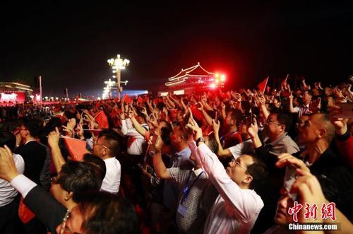 国庆70周年联欢活动于10月1日晚8时在天安门广场举行，整个联欢活动由主题表演、中心联欢表演、群众联欢、烟花表演四个功能表演区组成。图为民众观看璀璨烟花。中新社记者 汤彦俊 摄