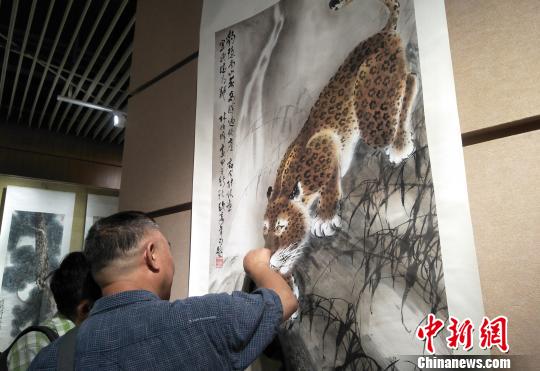 观众欣赏六尺国画挂轴《豹子觅泉图》。主办方供图