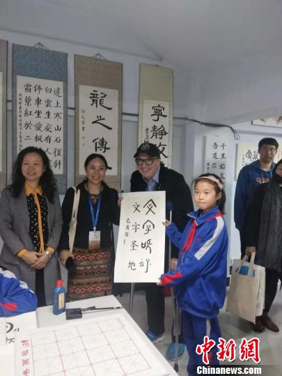 图为外国汉学家与孩子交流书法?！⊙畲笥?摄