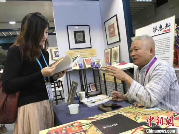 秀洲农民画画家缪惠新和参观者交流。供图