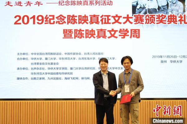 中华全国台湾同胞联谊会副会长郑平(左)为“陈映真思想与创作”论文一等奖获得者张立本颁奖?！×跖?摄