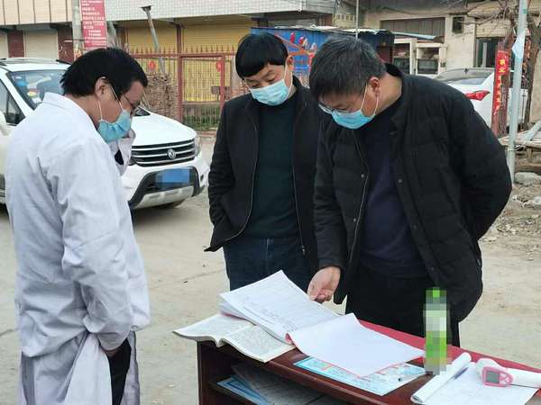 冯营乡党委书记李广君（左三）到卡点指挥棚查看过往人员体温信息登记情况