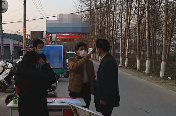 冯营行政村入村路口卡点值班人员为入村人员测量体温