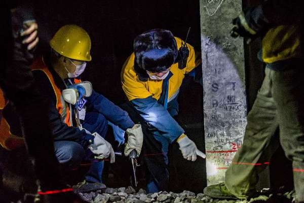 机械工队长侯宁与03506清筛车组车队长核对清筛后的线路标高，严把施工质量关。（摄影 贾佳）