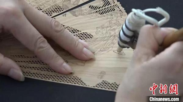 邢伟中的徒弟向观众展示檀香扇制作过程中的“烫花”过程。　徐明睿 摄