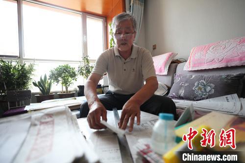 李竹庭正在用尺子撕扯报纸。　于晶 摄