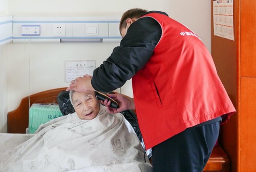 来自专业美发机构的志愿者们为老人进行理发