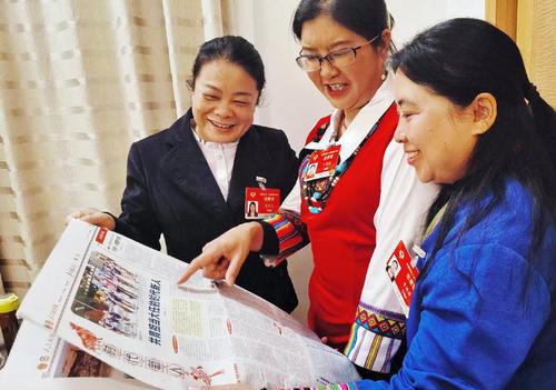 住滇全国政协委员黄丽云、丁秀花、资艳萍（从左至右）阅读人民政协报，就更好的培养孩子们成为新时代接班人等教育问题各抒己见。 特邀委员记者 茸芭莘那 摄