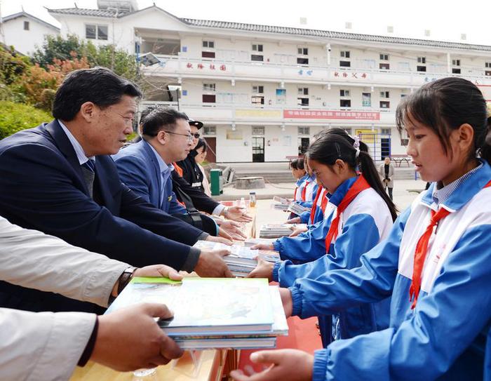 北京公益服务发展促进会常务副会长兼秘书长、北京市昌平区政协委员孙鹏飞（左二）及出席捐赠仪式的嘉宾向小学生捐赠图书