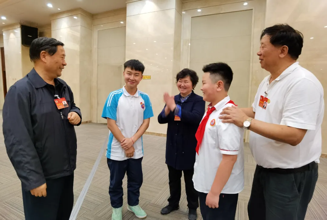 全国政协常委戚建国（左一）、全国政协文化文史和学习委员会副主任叶小文（右一）与学生亲切交谈