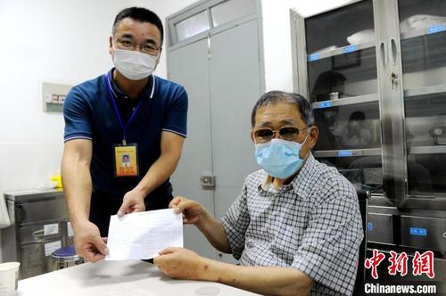 旧镇卫生院相关负责人把盖好章的预防接种凭证递给大陆知名台商李瑞河(右)?！≌沤鸫?摄