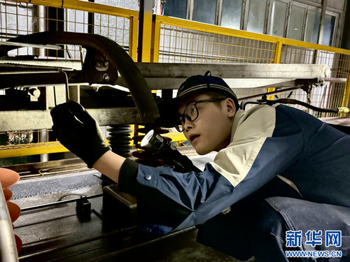 广州东动车运用所检修班组长丁帅检查动车组高压设备。新华网发 （谢荣浩 摄）