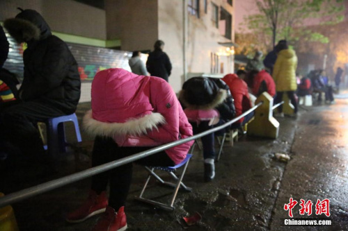 2016年4月6日，在西安市丈八四路缤纷南郡小区内的幼儿园后门附近，家长排队等待报名入园。图片来源：视觉中国
