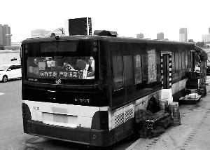 路边停放的公交车顶上的空调十分显眼，旁边码放着座椅、遮阳棚、啤酒等物?？导?摄